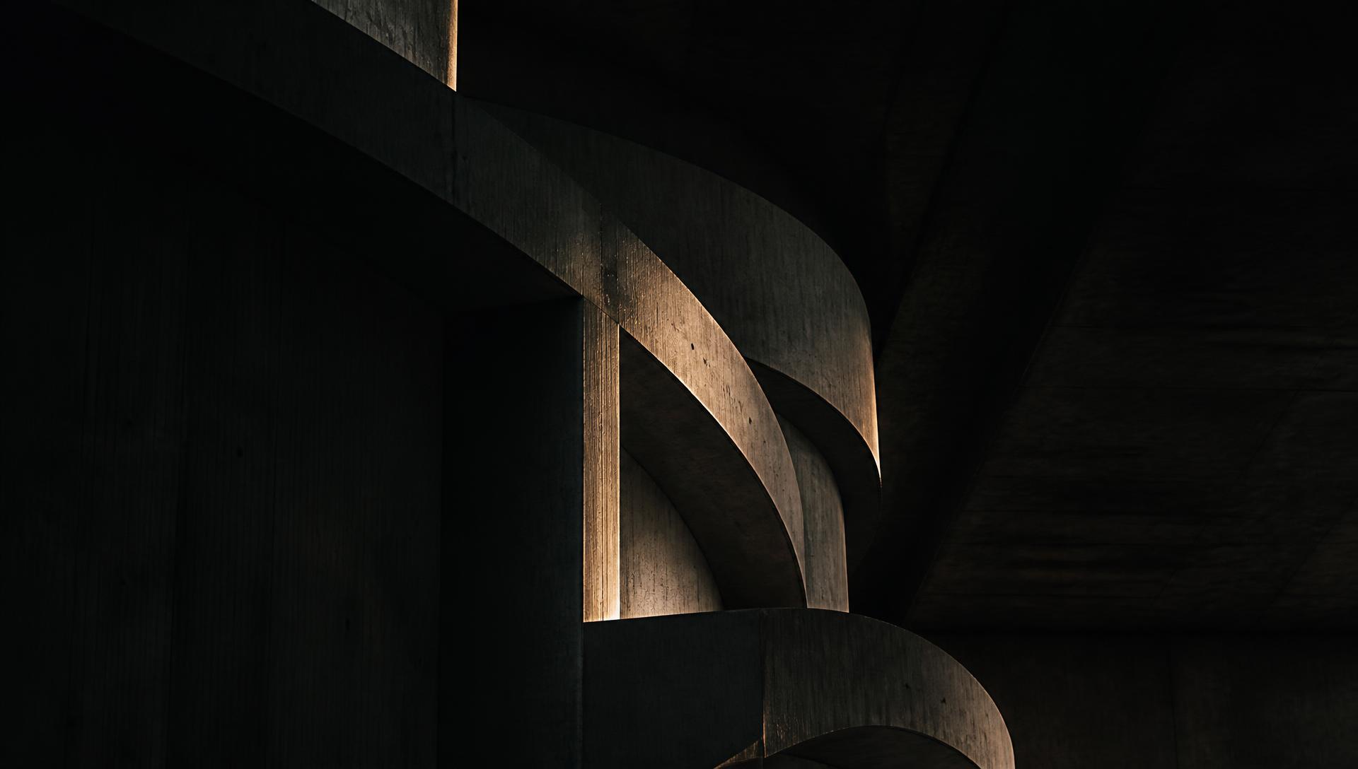 Structure architecturale monumentale en béton, lumière rasante